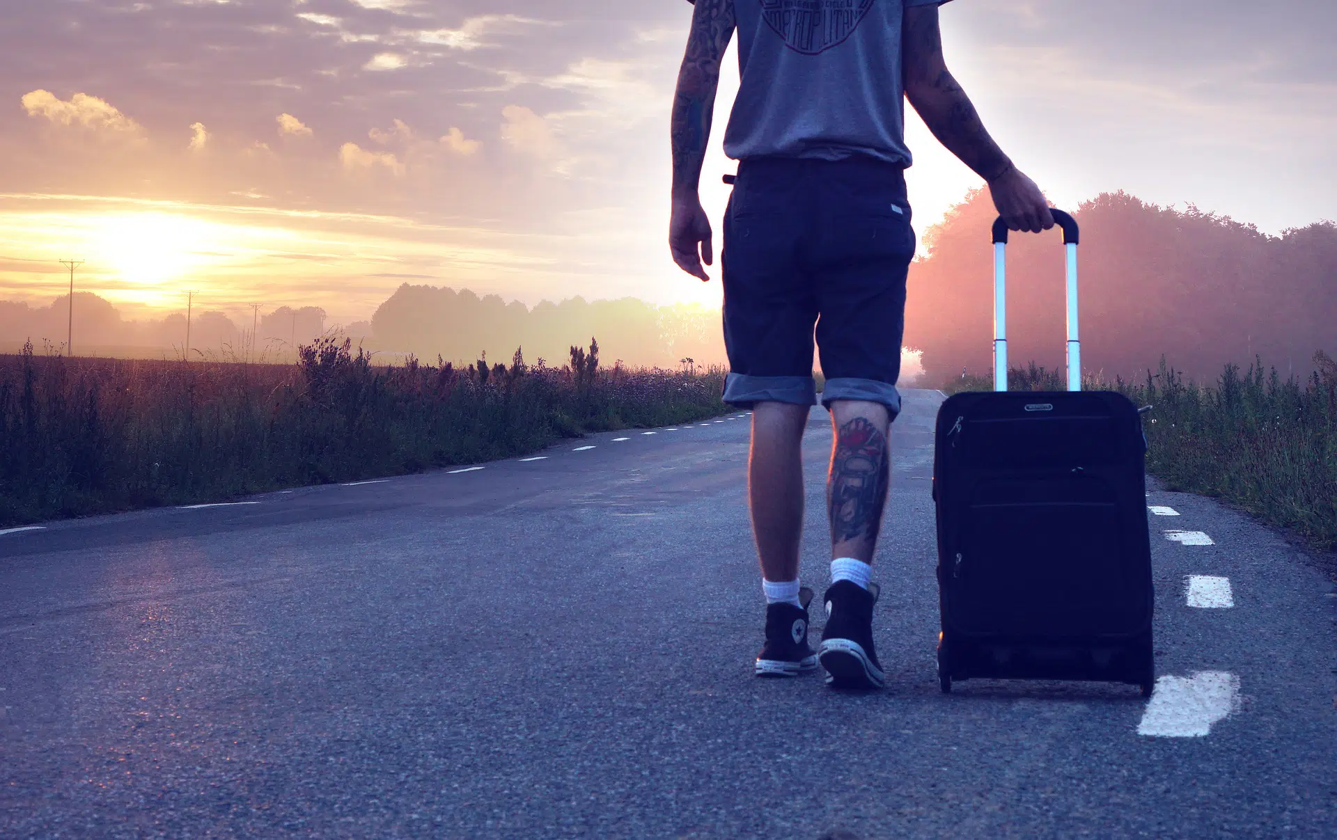 man with luggage walking down road