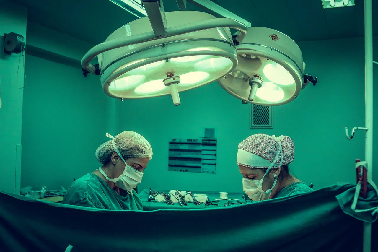 two doctors doing colorectal surgery behind curtain but not with defective hemorrhoid stapler