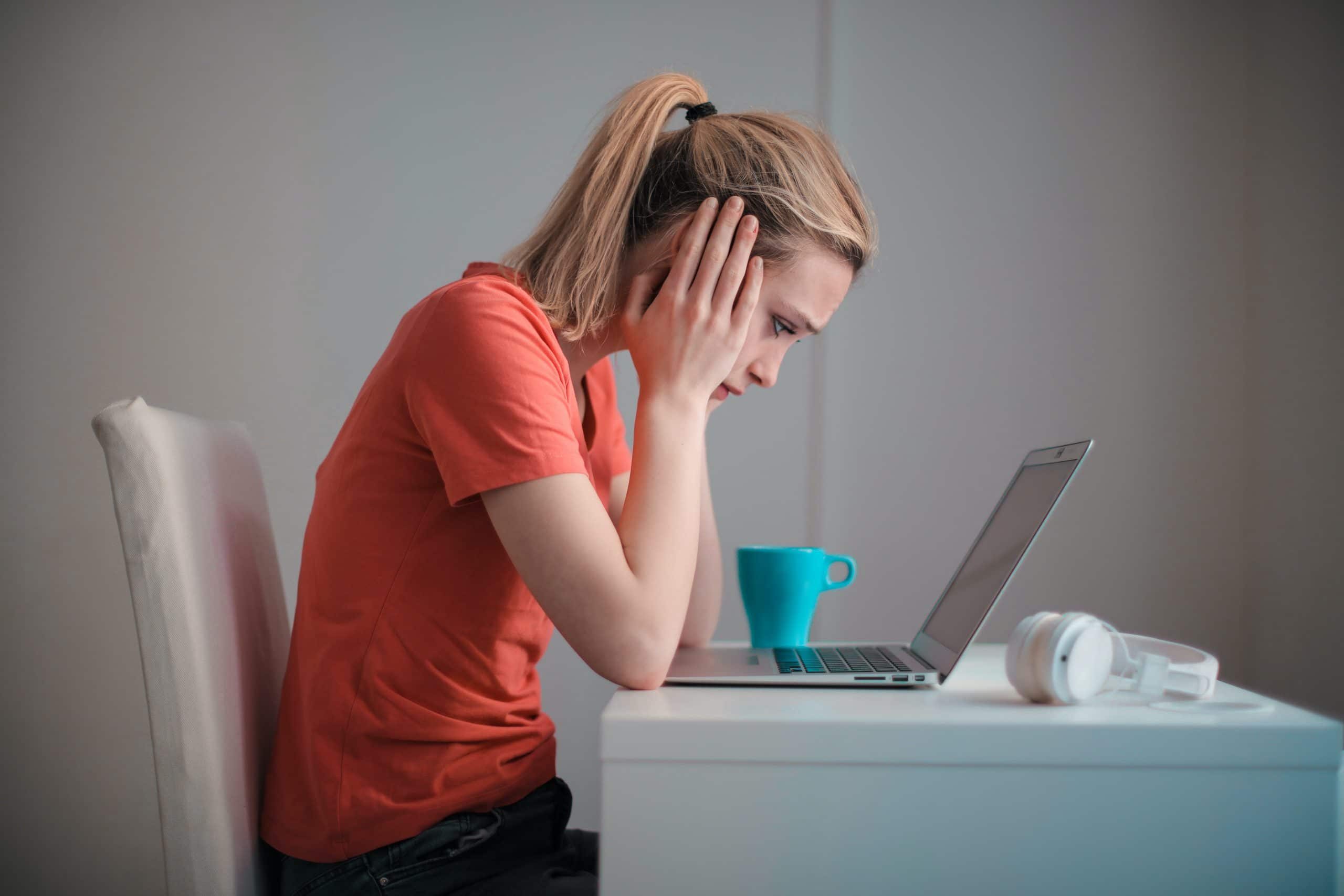 Woman looking at her laptop, frustrated after making a costly mistake in settling a car accident without a lawyer