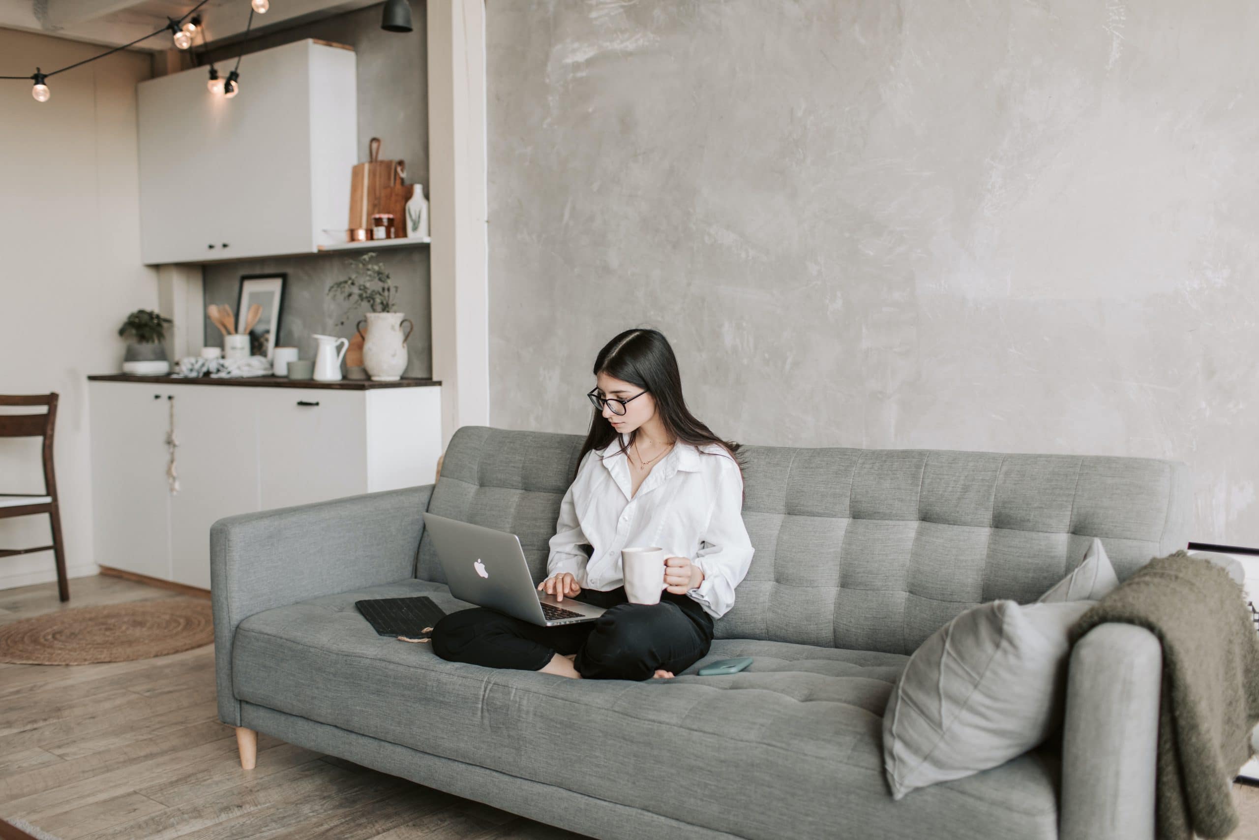 Woman sitting on a couch with a laptop open, finding an attorney after a car accident