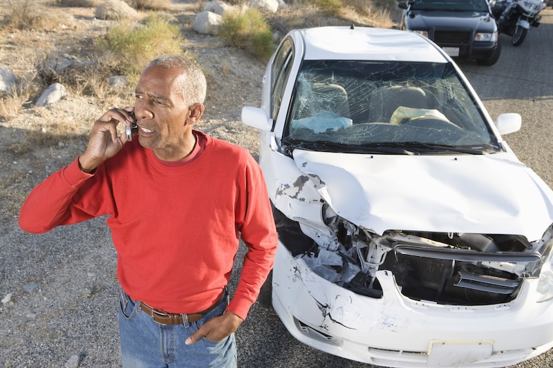 A Man Calling Someone Standing By His Crashed Car