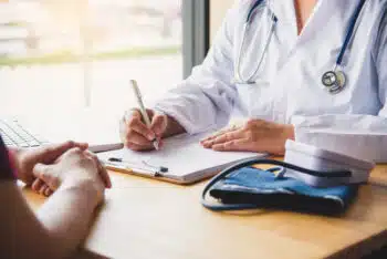 Cropped image of a doctor and patient speaking across a desk