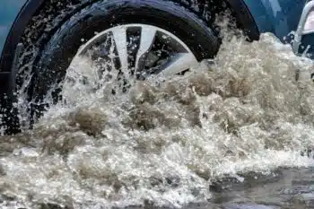 Close-up of car wheel driving through flooded street
